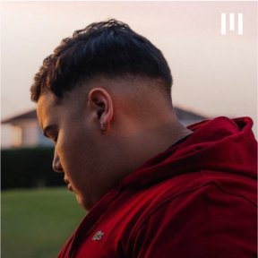 UnitedMasters Artist Floymenor in a dark red hoodie looking down to the left. 